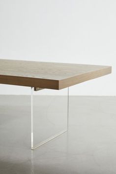 a wooden table sitting on top of a cement floor next to a white wall in an empty room