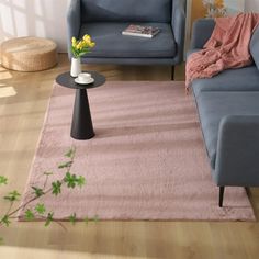 a living room with two blue couches and a pink rug