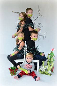 a group of children with masks on their faces sitting in front of a christmas tree