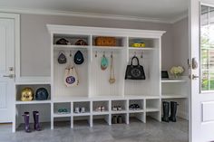 an entryway with several white shelves and purses