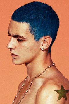 a young man with blue hair and piercings on his ear, wearing a necklace