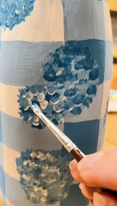 someone is painting a vase with blue and white stripes