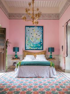 a bed in a room with pink walls and green lamps on either side of the bed