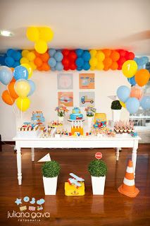 a table topped with lots of balloons next to a cake and cupcakes on top of it