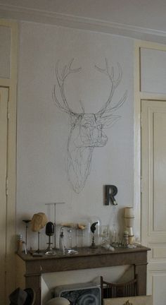 a drawing of a deer's head on the wall above a fireplace