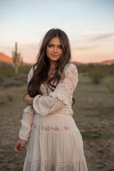 a beautiful young woman standing in the desert