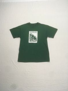 vintage 1990s t-shirt Clair Tapaan Lodge Donner Summit Established 1934 green tee w/white print image of 2 campers w/mountain peaks in the background good vintage condition w/some wear-small stain/paint spots-see photos no tag, cotton feel , single stitch fits like a xs/s-see below measures, lying flat, shoulder-18" chest-18" sleeve-7" length-26 1/2" Green Graphic Print Outdoor T-shirt, Outdoor Green T-shirt With Graphic Print, Green Graphic Print T-shirt For Outdoor, Green Graphic Tee For Outdoor, Green T-shirt For Outdoor Activities, Green Short Sleeve T-shirt For Outdoor, Green Crew Neck T-shirt For Outdoor Activities, Green Crew Neck T-shirt For Outdoor, Green Letter Print T-shirt For Camping