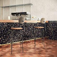 two stools sitting next to each other in front of a counter with a coffee machine on it