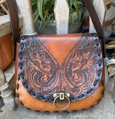 This vintage handmade leather purse is a perfect addition to any boho, western or hippie outfit. The exterior of the bag is tooled leather in a brown color. The flap is beautifully tooled and has a brass lock closureI added new lacing and a new adjustable strapthe leather was oiled and conditioned... The medium-sized hobo bag has a single leather strap in a matching brown color, adding to the overall vintage vibe of the product. This unique bag is perfect for the free-spirited cowgirl or hippie at heart. Add this beautiful piece to your collection today! Measurements are 10 inches across, 9 inches tall, the gusset is 2 inches and the strap is long so it can be worn as a shoulder or crossbody bag...the strap is adjustable Western Style Hand Tooled Brown Bag, Western Style Hand Tooled Brown Shoulder Bag, Western Style Brown Hand Tooled Shoulder Bag, Leather Hand Tooled Shoulder Bag For Western-themed Events, Western Style Hand Tooled Shoulder Bag For Travel, Western Brown Bag With Adjustable Strap, Western-themed Brown Leather Shoulder Bag, Western Brown Satchel Shoulder Bag, Western Style Brown Satchel Bag