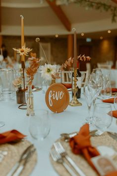 Table number sign on terracotta plate surrounded by taper candles and dried flower arrangements for boho wedding Terracotta Wedding Table Numbers, Autumn Table Numbers, Table Setting Fall Wedding, Autumn Wedding Round Table Decorations, Terracotta Table Numbers, Orange Wedding Table Decor, Wedding Table Decorations Boho, Terracotta Wedding Table Settings, Table Decorations Boho