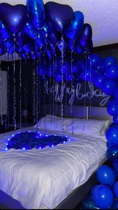 blue balloons and streamers are hanging from the ceiling above a bed in a bedroom