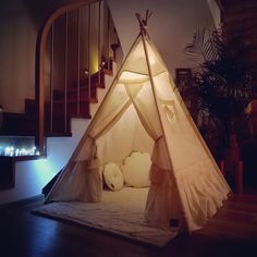 a teepee tent sitting on top of a wooden floor in a living room next to stairs