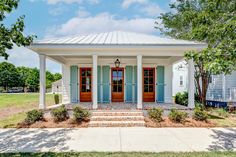 a small white house with red doors and pillars