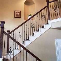 a stair case next to a white wall with a framed picture on the wall above it