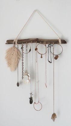 a wall hanging with various necklaces and rings on it's side, attached to a wooden branch