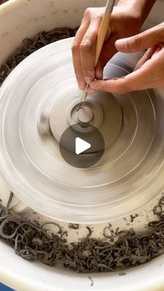 a person working on a pottery wheel with a wooden stick in their hand and the video below it