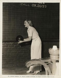 an old black and white photo of a woman holding a ball in front of a chalkboard