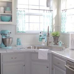 a kitchen with white cabinets and blue accessories on the counter top, along with a silver dishwasher