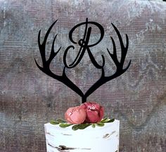 a wedding cake with antlers and two roses on top is decorated in white frosting