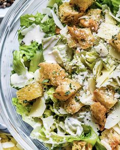 a salad in a bowl with dressing and croutons on the side, ready to be eaten