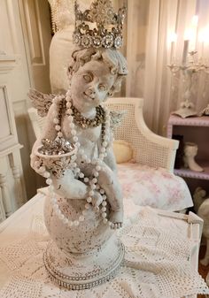 a white statue sitting on top of a table next to a chair and chandelier