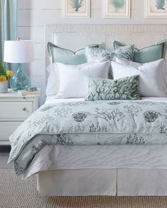 a bed with white and blue comforters, pillows and pictures on the wall behind it