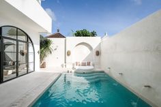 an outdoor swimming pool surrounded by white walls