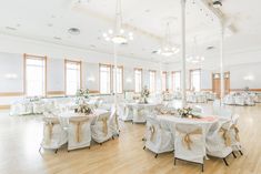 the banquet hall is decorated with white linens and gold sashes, as well as floral centerpieces