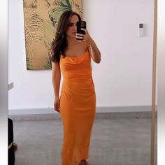 a woman in an orange dress taking a selfie