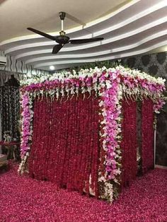 an arrangement of flowers and greenery on display in a living room with a ceiling fan