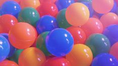 many different colored balls are in the air and one is orange, green, blue, and pink