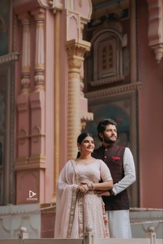 a man and woman standing next to each other in front of a building