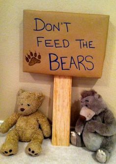 two teddy bears sitting next to a sign that says don't feed the bears