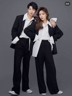 two people standing next to each other in black and white outfits