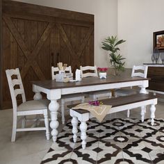 a dining room table with chairs and a bench in front of a wooden door on the wall