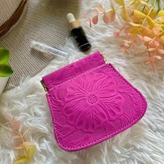 a pink purse sitting on top of a white fur covered floor next to some flowers