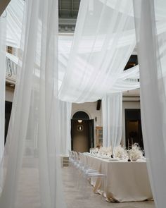 the tables are set with white tablecloths and place settings for an elegant dinner