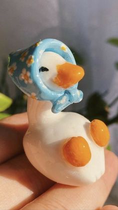 a close up of a person holding a small toy duck in their hand with flowers on it