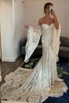 a woman is taking a selfie in her wedding dress with an open back and long sleeves