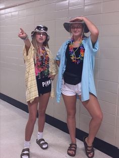 two young women standing next to each other in front of a wall