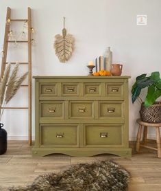 a green dresser sitting on top of a hard wood floor next to a wooden ladder