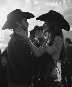 black and white photograph of two people in cowboy hats dancing at a party with other people