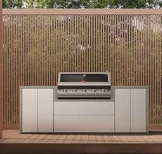 an outdoor bbq with grill and cabinets in front of a wooden fenced area