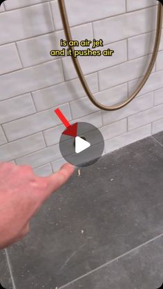 a person is pointing to an air jet and it pushes air on the floor in front of a brick wall