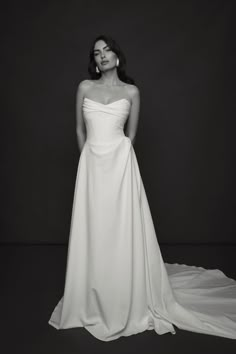 a woman in a white wedding dress posing for a black and white photo with her hands on her hips