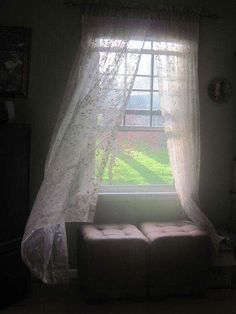 a window with sheer curtains and a couch in front of it