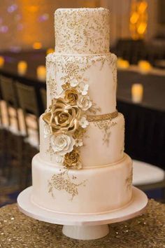 a three tiered wedding cake with gold flowers on the top and bottom, sitting on a table