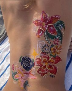 the back of a woman's body with flowers painted on her stomach and chest