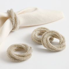 two pieces of jewelry sitting on top of a white cloth