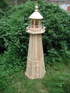 a small wooden lighthouse sitting in the grass